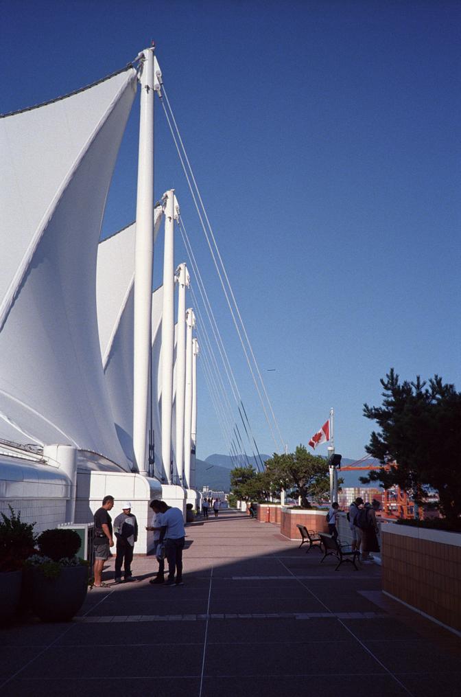 Some people standing under the awning on the docks, talking