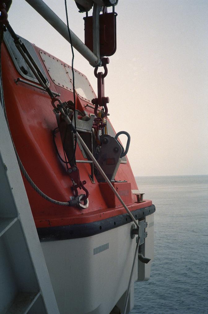 An orange and white lifeboat with the ocean in the background