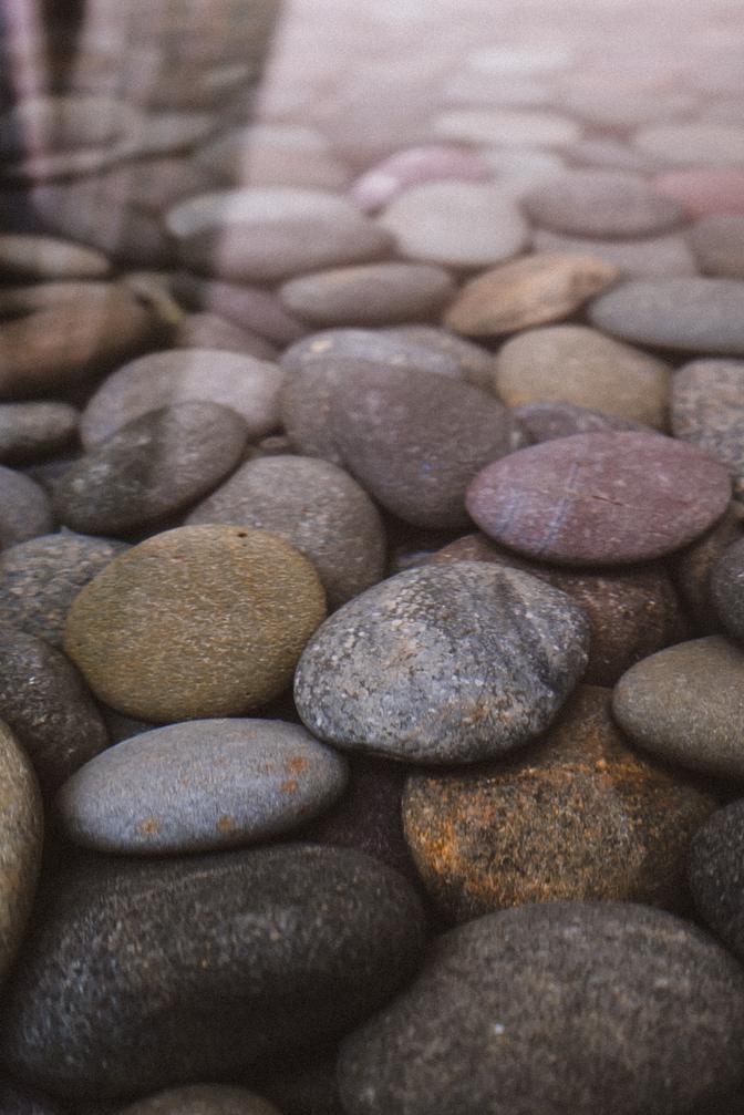 Round stones underwater, with an interesting glare