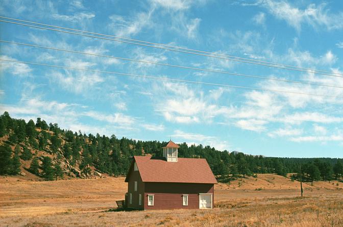 A small red building in the middle of a field of yellow grass